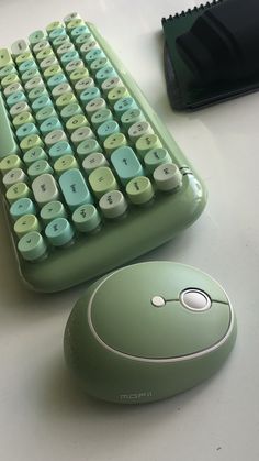 a green computer keyboard sitting next to a mouse on top of a white countertop