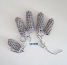 four crocheted mittens are tied together on a white surface with the word hooked written in blue