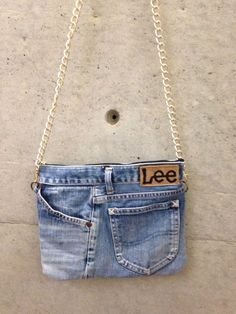 a small purse with the word lee on it hanging from a chain attached to a wall