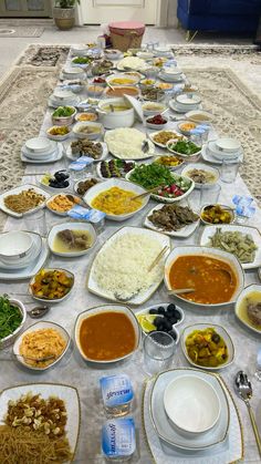 a long table filled with lots of food on top of a white tablecloth covered floor