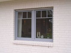 two vases sit in the window sill of a white brick building with blue trim