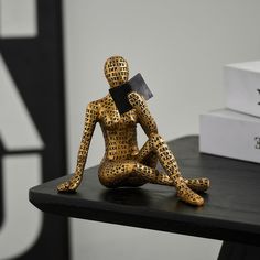 a wooden statue sitting on top of a black table next to a white box and some books