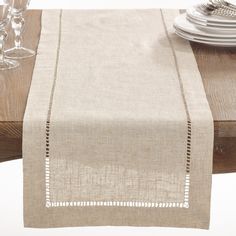 the table is set with white plates and silverware, along with a beige linen runner