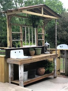 an outdoor kitchen with potted plants on the counter and sink in the back yard