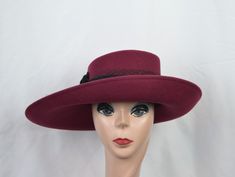 This unique shape burgundy wide-brimmed wool felt hat would be perfect for any special occasion. The measurements are 16 inches by 12 inches. The hat is trimmed with a black grosgrain ribbon band, black velvet flowers, and netting all around the band. The hat will fit up to a 22 5/8 inch head size and has a sizing cord inside to adjust to your head size. Burgundy Flat Brim Felt Hat For Fall, Fitted Burgundy Fedora Hat, Burgundy Fedora Felt Hat For Fall, Fitted High Crown Felt Hat For Fall, Fall Burgundy Felt Hat With Curved Brim, Fitted Burgundy Brimmed Hat, Burgundy Curved Brim Hat For Kentucky Derby, Elegant Wide Brim Burgundy Hat, Burgundy Fitted Hat