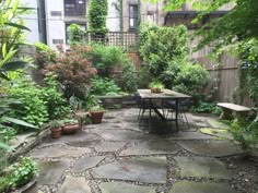 an outdoor patio with tables and chairs surrounded by greenery