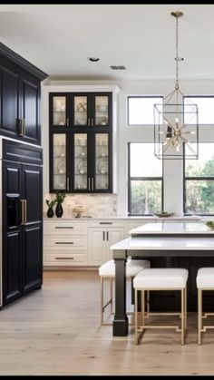 a large kitchen with black cabinets and white counter tops