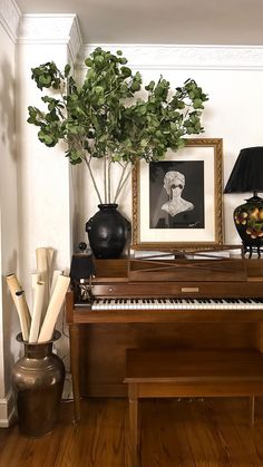 a room with a piano, vases and pictures on the wall next to it