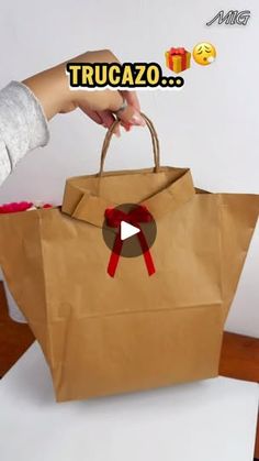 a person holding a brown paper bag with a red bow on it's handle