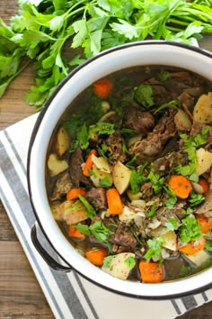 a white bowl filled with meat and vegetables on top of a table next to some parsley