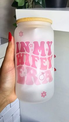 a hand holding a jar with the words tiny wife in pink and white on it