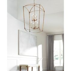 a chandelier hanging from the ceiling in a room with white walls and wooden floors