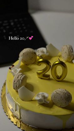 a yellow cake with white frosting and gold decorations on it's top that says hello 20