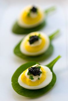 small deviled eggs with black cavia on green leaves