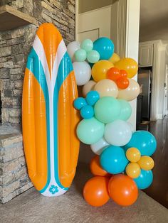 an inflatable surfboard and balloons are on the floor next to a fireplace