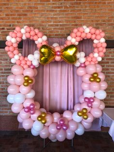 the balloon arch is decorated with pink, white and gold balloons in front of a brick wall