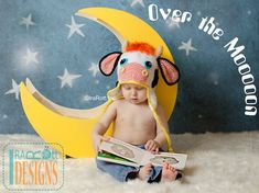 a baby is sitting on the moon reading a book