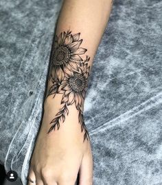 a sunflower tattoo on the left wrist and right hand is shown with black ink