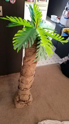 a palm tree made out of toilet paper on the floor in front of a desk