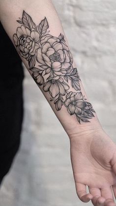 a black and white flower tattoo on the left arm, with leaves around it's edges