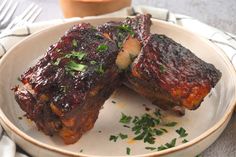 two pieces of ribs on a plate with parsley