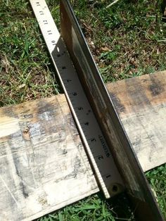 a wooden ruler sitting on top of grass next to a piece of wood that has been cut in half