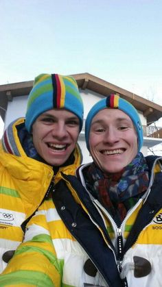 two men standing next to each other in front of a snow covered ski lodge and building