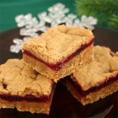 three pieces of dessert sitting on top of a black plate with snowflakes in the background