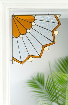 an orange and white fan hanging from the side of a wall next to a green plant