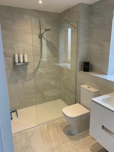 a bathroom with a toilet, sink and shower in it's glass walled area