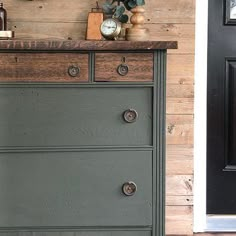 an old dresser is painted green and has knobs on the drawers, along with a clock