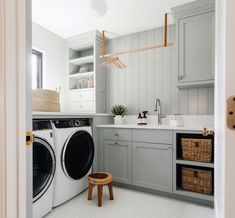 a washer and dryer in a small room with white walls, cabinets and drawers