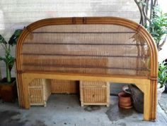 a bed frame made out of bamboo and wicker with plants in the back ground