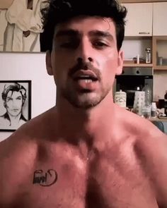 a man with no shirt on standing in a kitchen