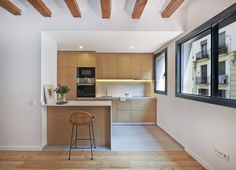 an empty kitchen with wooden floors and white walls, along with a bar stool in front of the counter