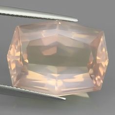 a large pink diamond sitting on top of a white table next to a pair of scissors