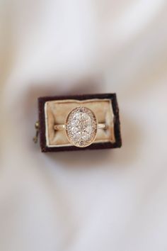 an engagement ring in a box on a white cloth covered surface with a diamond center