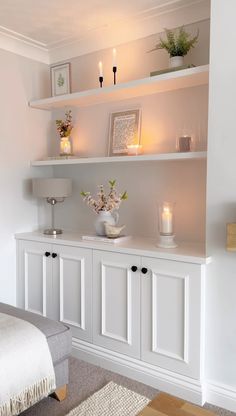 a white shelf with candles and pictures on it