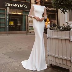 a woman in a white dress standing on the street