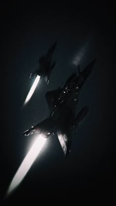 two fighter jets flying through the air at night