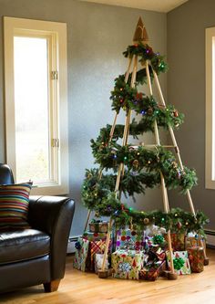 a christmas tree made out of ladders with presents on the floor next to it