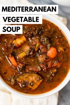 a white bowl filled with vegetable soup on top of a table next to a napkin