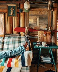 a person laying on top of a couch next to a table with a clock above it