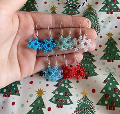 small beaded christmas tree earrings in various colors and sizes on a person's hand