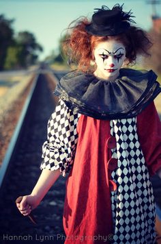 a woman dressed as a clown walking down train tracks