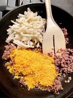 some food is cooking in a skillet with a spatula next to it on the stove