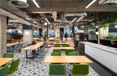 an office with green and yellow chairs, plants on the wall and people walking in the distance