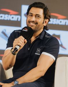 a man sitting in front of a microphone on top of a white chair and smiling