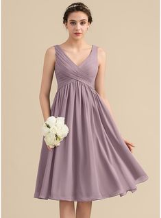 a bridesmaid in a short purple dress holding a white bouquet and posing for the camera