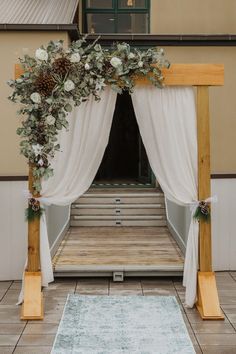 a wedding arch with white flowers and greenery on the front door entrance to a building